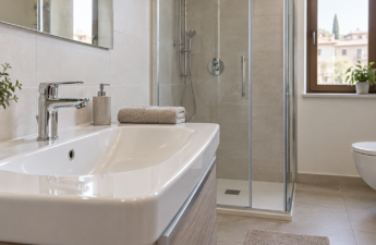 Lavabo e doccia di un bagno domestico luminoso con rubinetteria integra